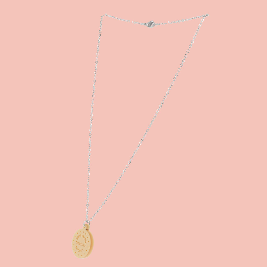 Necklace with a digestive biscuit pendant on a pink background