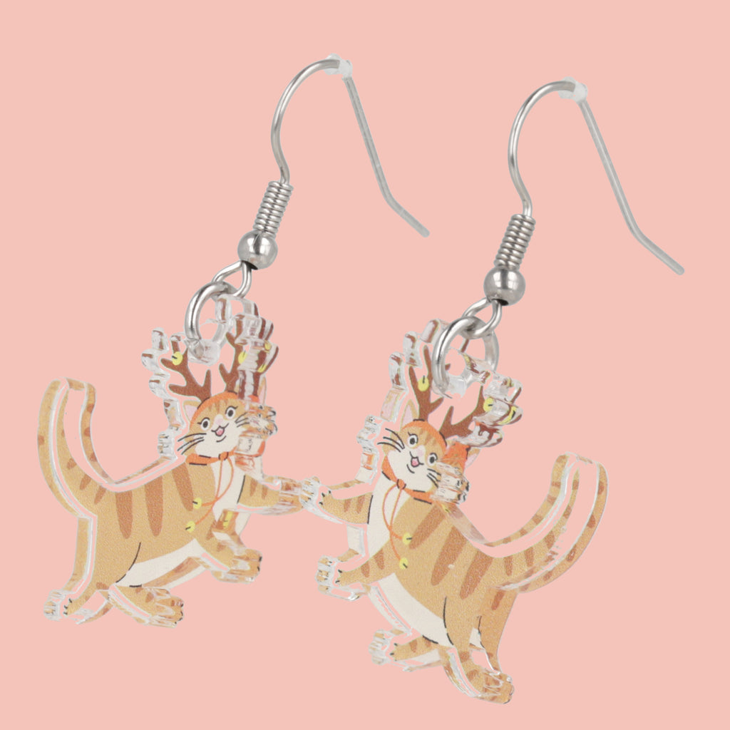 Cat-shaped earrings on a pink background