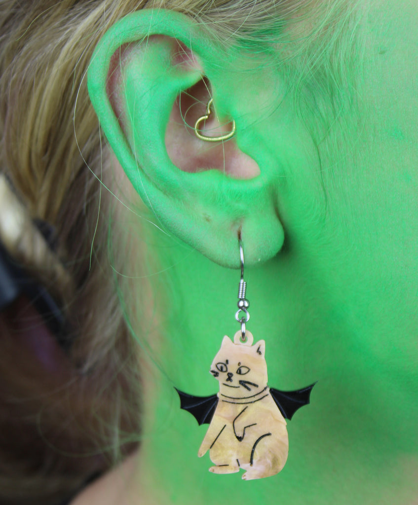 Ear wearing Ginger cat charm with bat wings on stainless steel earwires