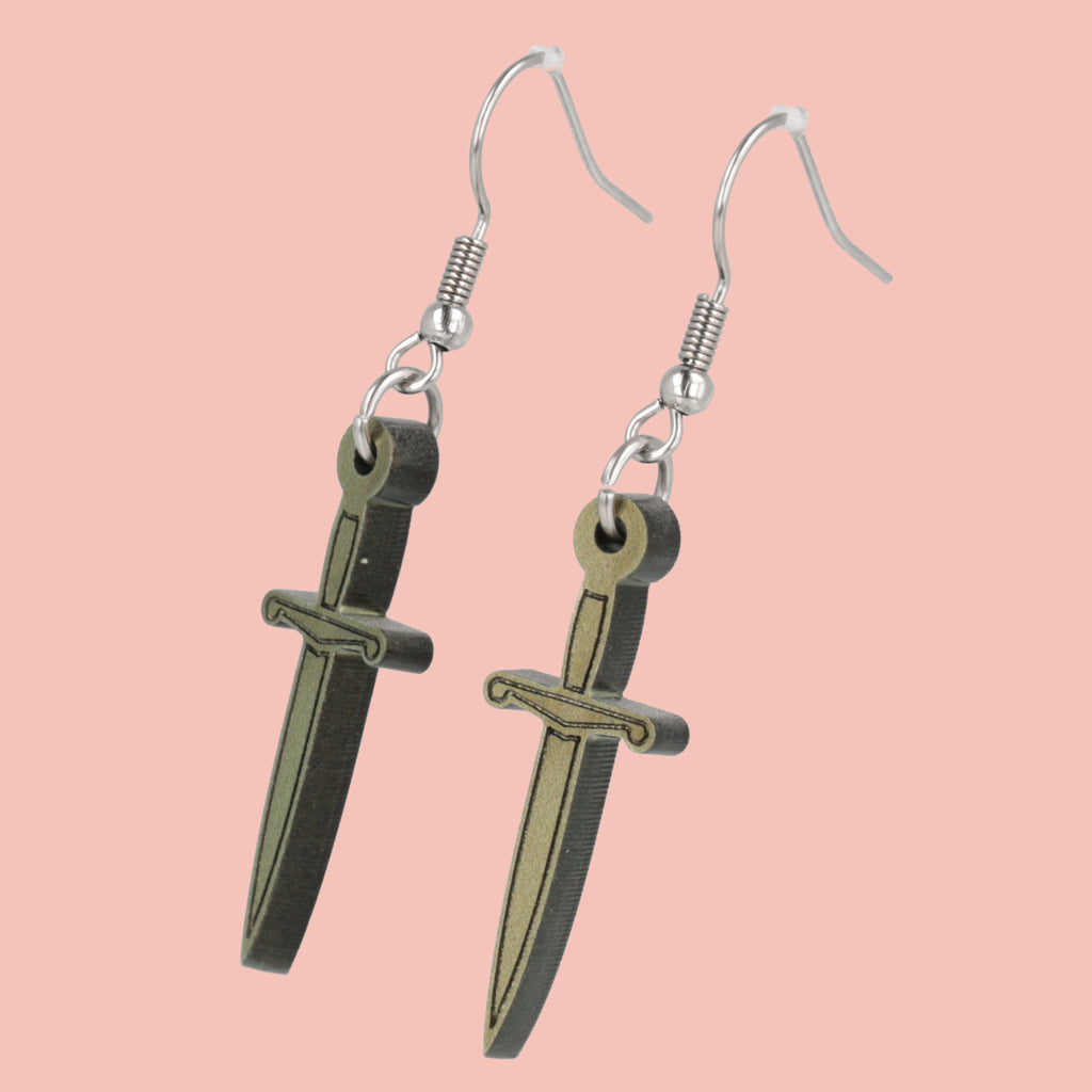 Dagger-shaped earrings on a pink background