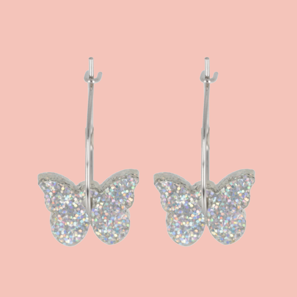 Butterfly-shaped earrings with glittery finish on a pink background