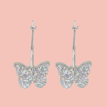 Butterfly-shaped earrings with glittery finish on a pink background
