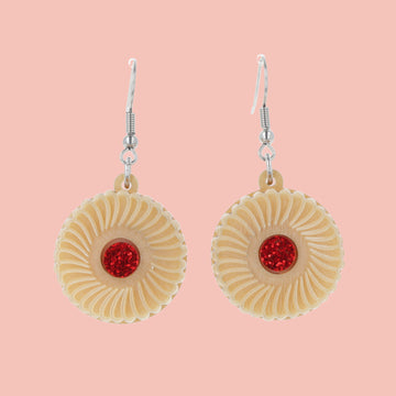 Pair of earrings with jam and cream biscuit charms on a pink background