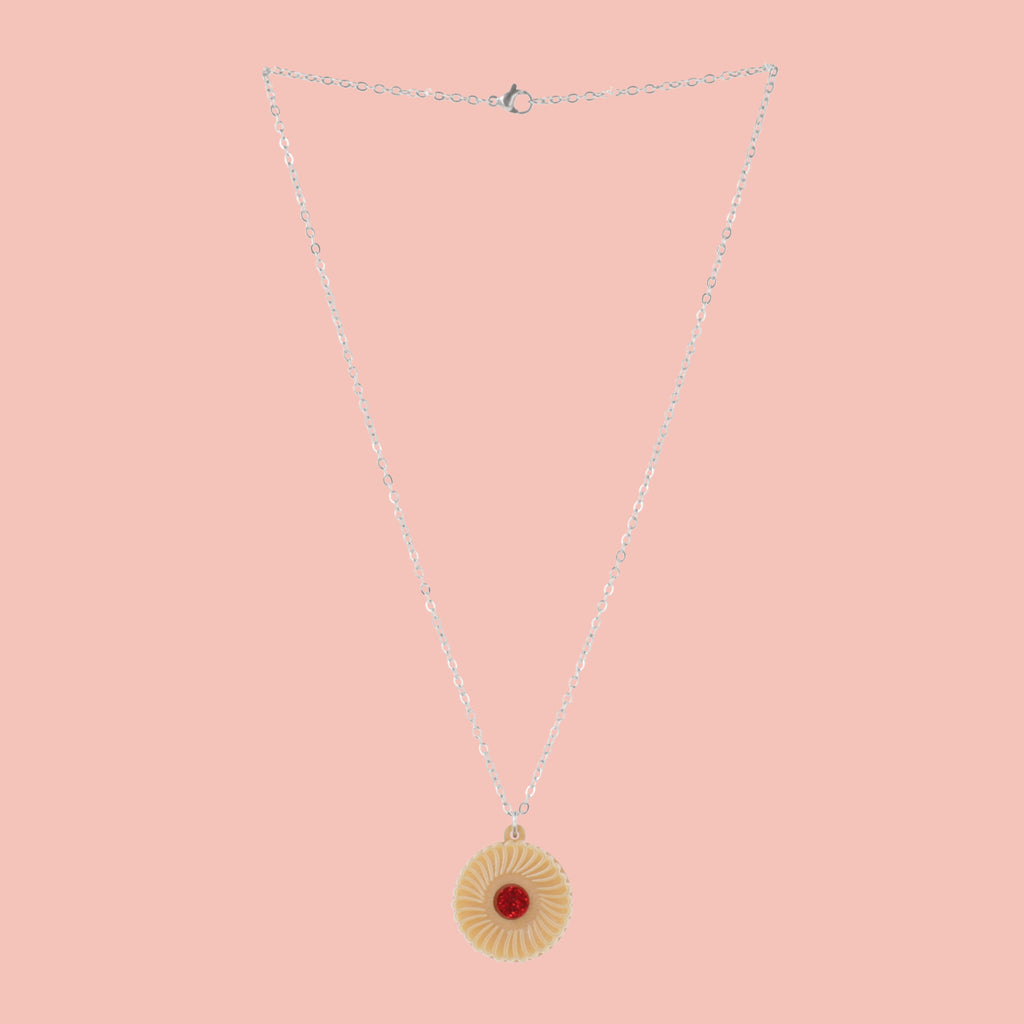 Necklace featuring a pendant of a jam and cream biscuit, on a pink background