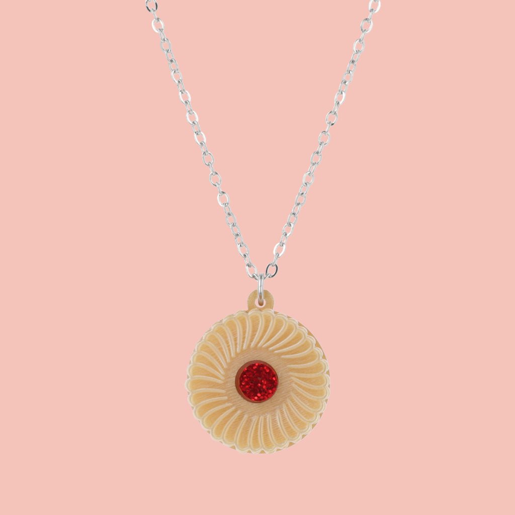 Necklace featuring a pendant of a jam and cream biscuit, on a pink background