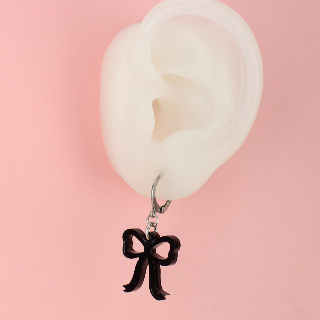 Ear wearing Black bow charms on stainless steel huggie hoops