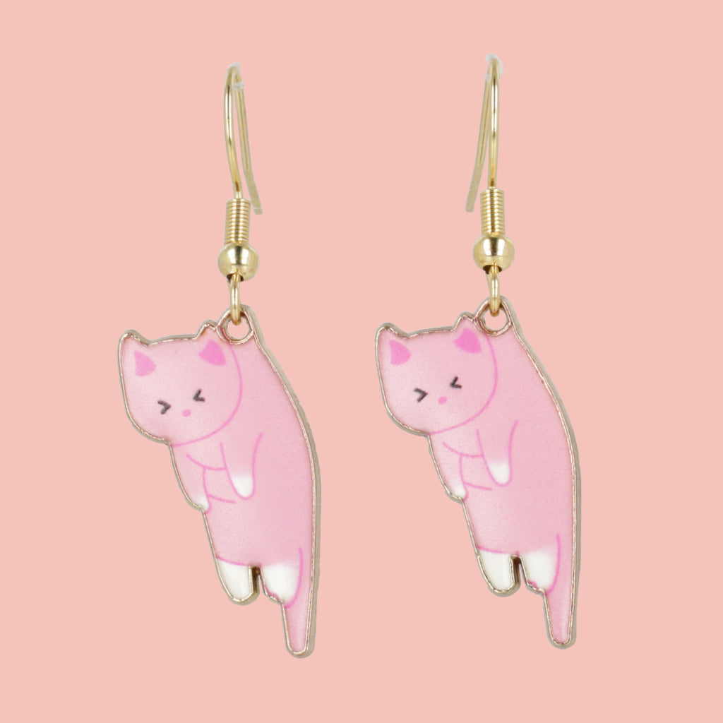 Pink cat-shaped earrings on a pink background