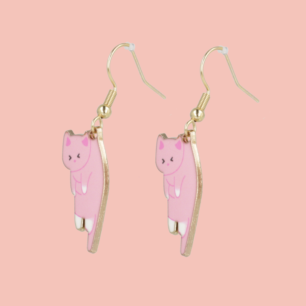 Pink cat-shaped earrings with gold hooks on a pink background