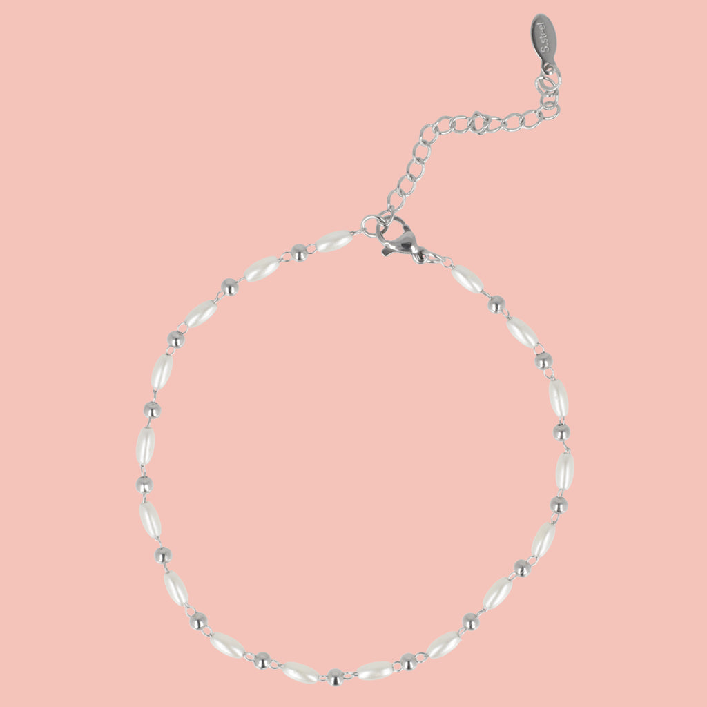 Silver anklet with white beads on a pink background