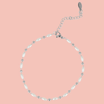 Silver anklet with white beads on a pink background