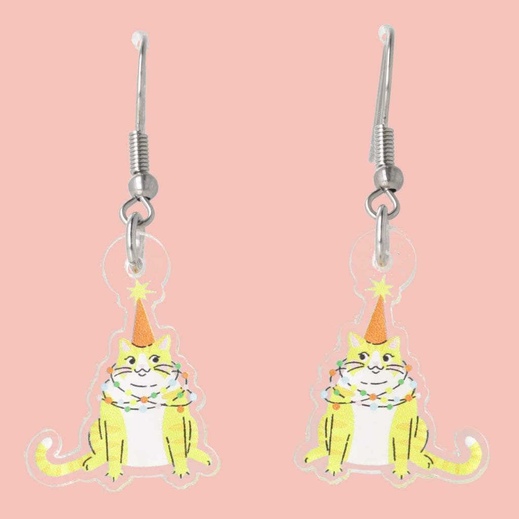Cat-themed earrings with festive hats on a pink background
