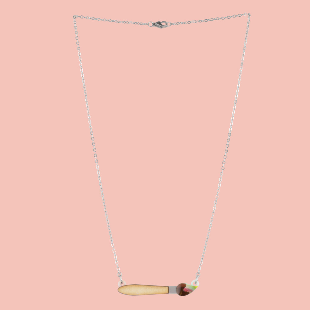 Necklace with a unique pendant shaped like a paintbrush on a pink background