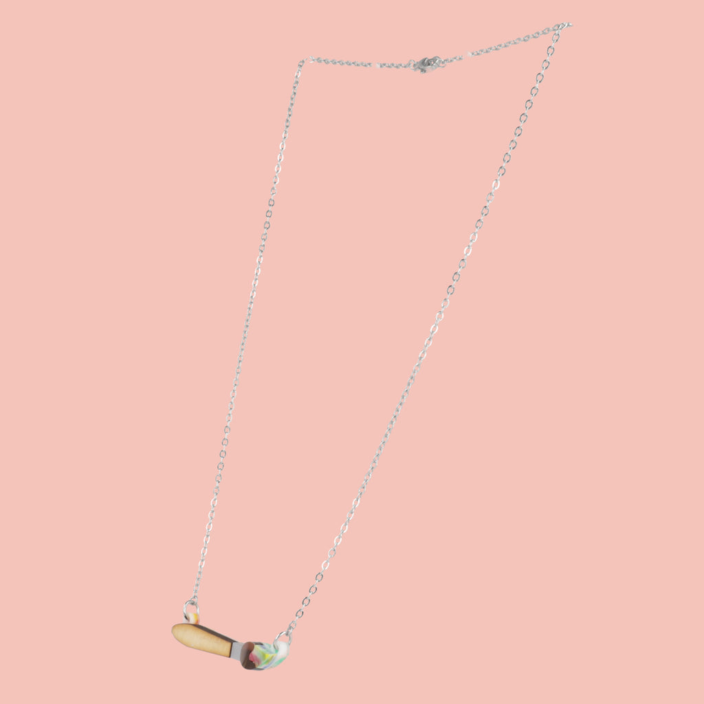 Necklace with a unique pendant shaped like a paintbrush on a pink background