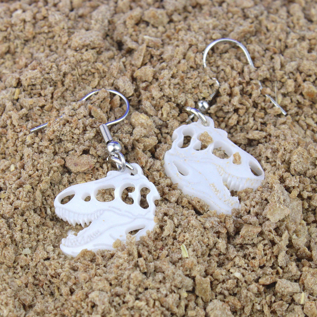 White Marble Perspex T-Rex Charms on stainless steel earwires shown in sand