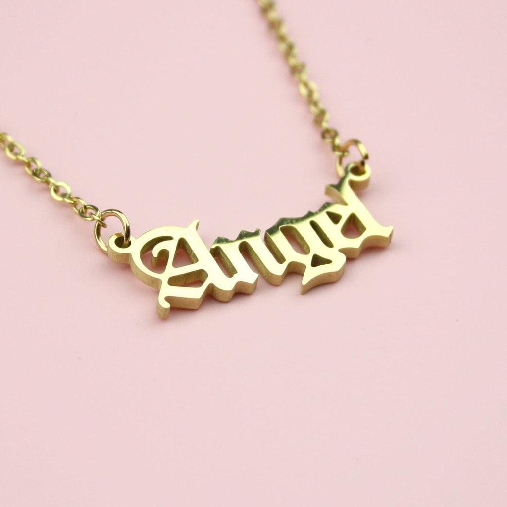 Gold plated stainless steel necklace with the word 'angel' written in a gothic font