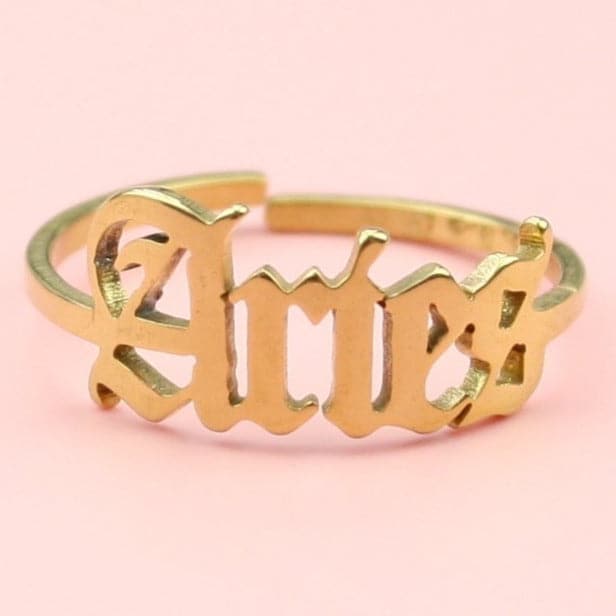 Gold plated stainless steel ring with 'Aries' written in an old english font