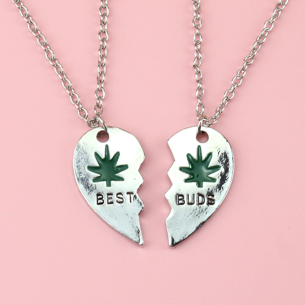 2 broken heart pendants, joining to make one. The left one reads 'BEST' and the right reads 'BUDS'. They both feature a green hemp design and black writing.
