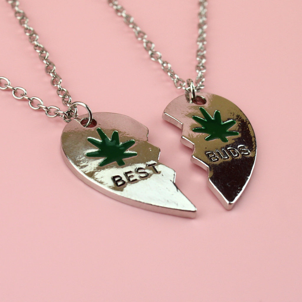 2 broken heart pendants, joining to make one. The left one reads 'BEST' and the right reads 'BUDS'. They both feature a green hemp design and black writing.