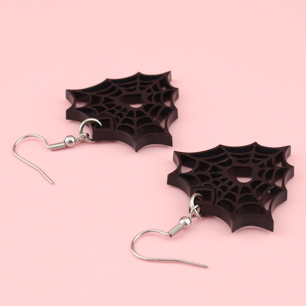 Black perspex spider web charms on stainless steel earwires with a cut out spiders web and heart centre