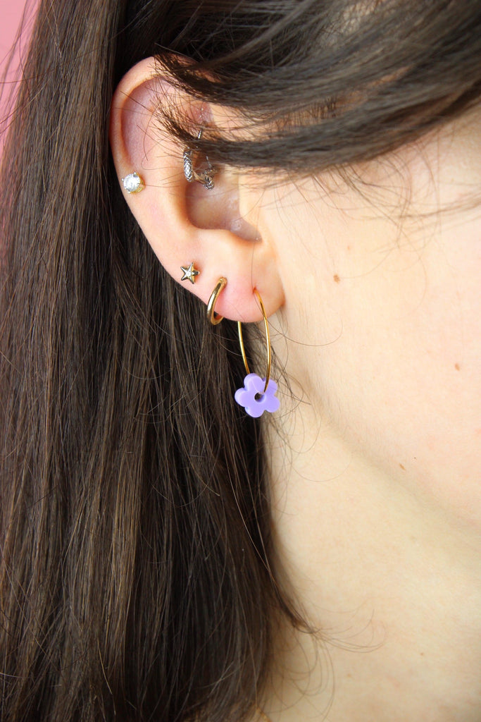 ear wearing the gold hoop with the purple flower charm