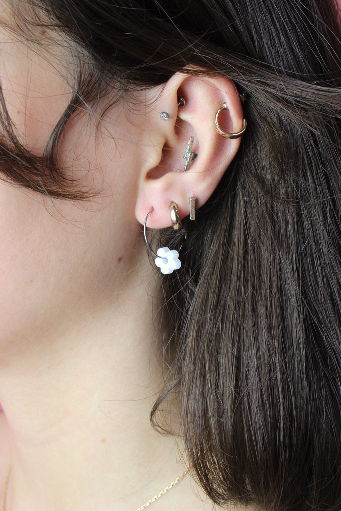 Model wearing white flower charm on silver hoop