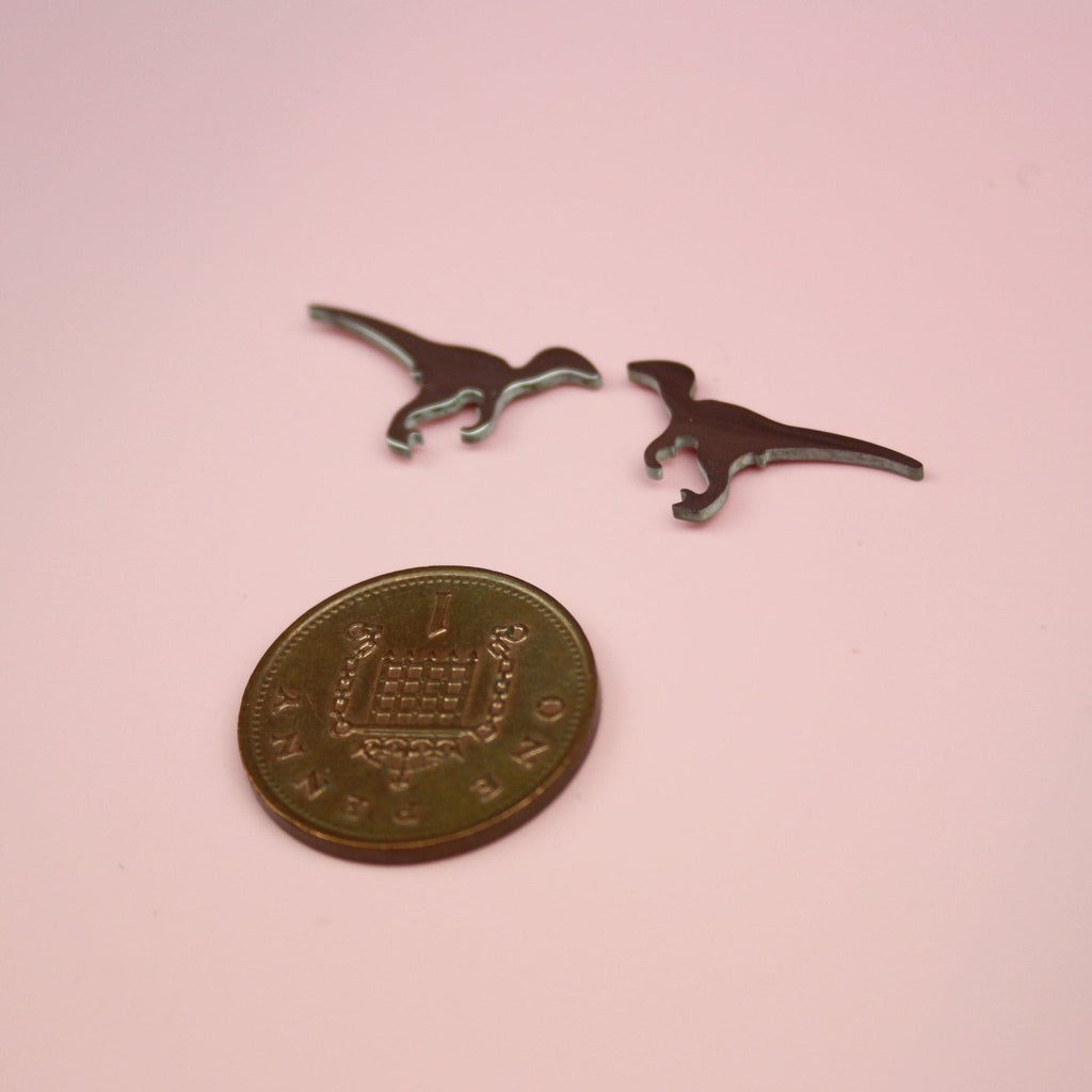 Velociraptor Stud Earrings with a penny underneath them for scale