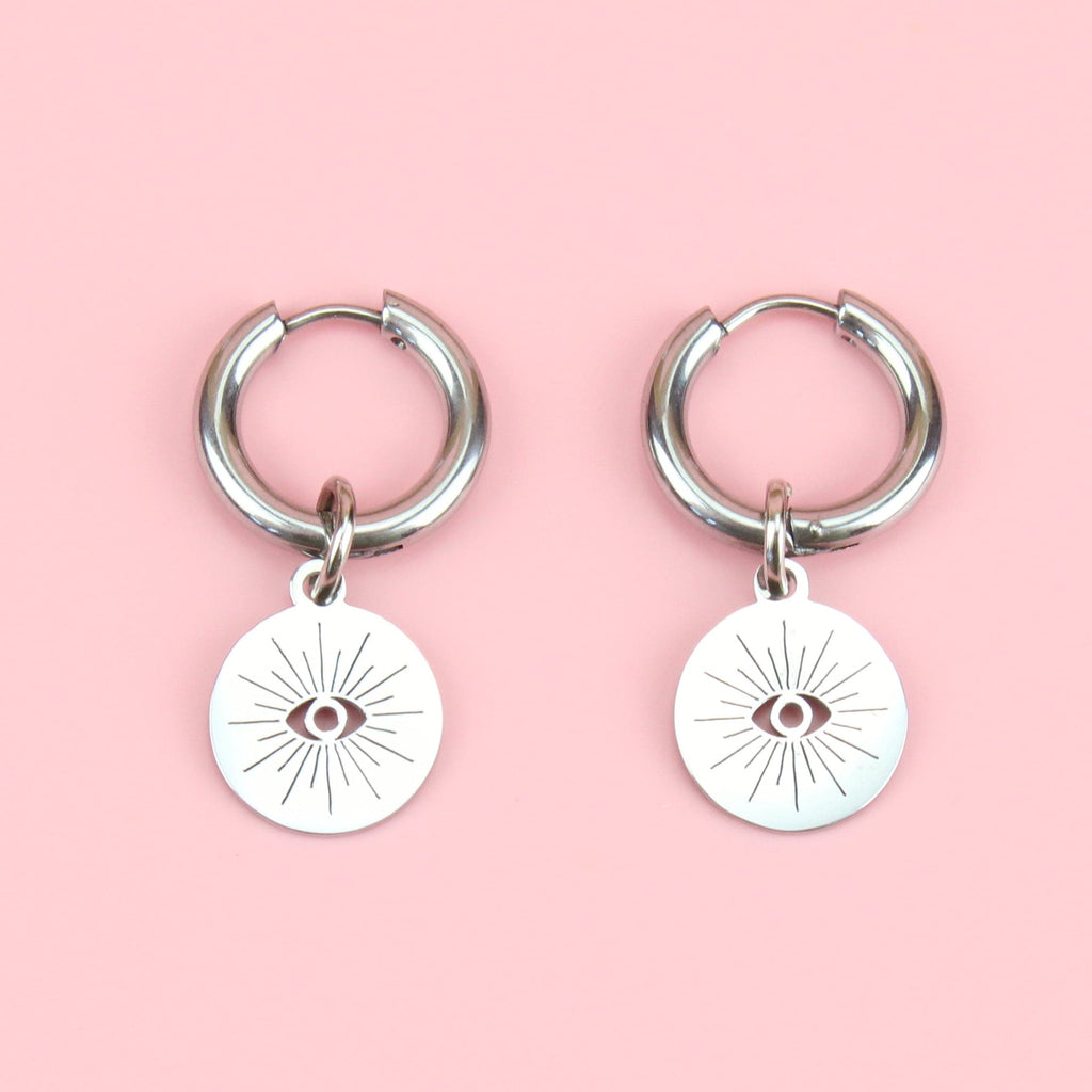 atainless steel hoops with a circular charm featuring a cut out evil eye 