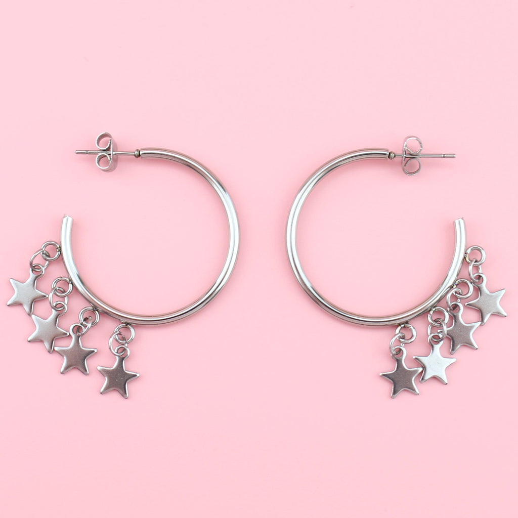Stainless steel stud hoops with four star charms dangling from the hoop