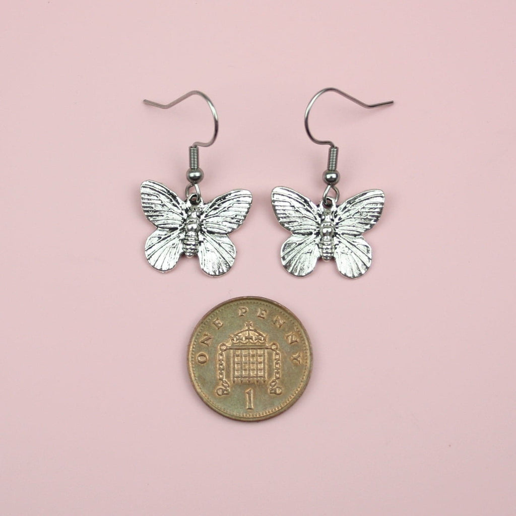Stainless butterfly charms on stainless steel earwires with a penny underneath to measure the size