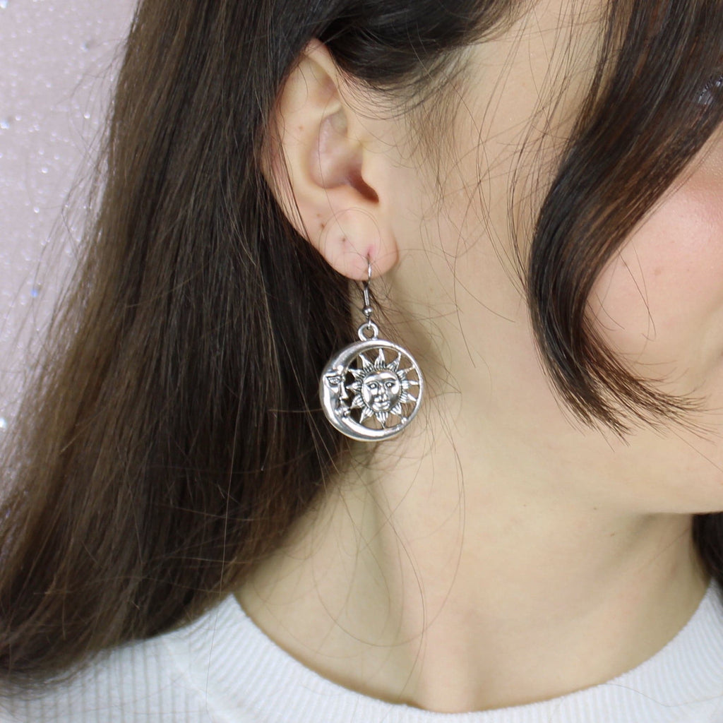 Sun face charm with a crescent moon face surrounding it on stainless steel earwires
