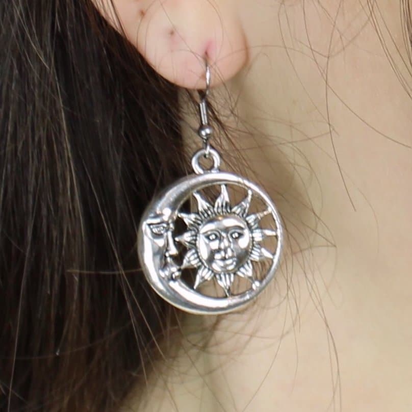 Model wearing Sun face charm with a crescent moon face surrounding it on stainless steel earwires