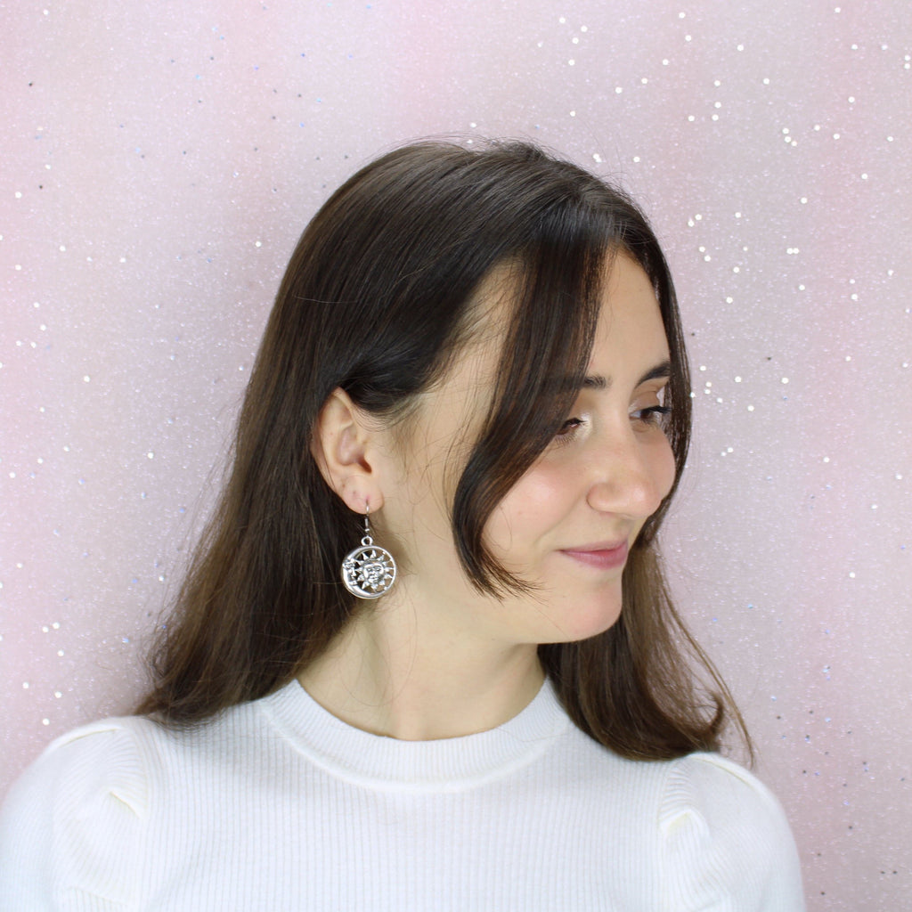 Model wearing Sun face charm with a crescent moon face surrounding it on stainless steel earwires