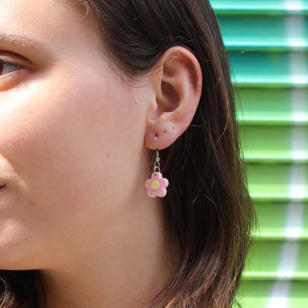Model wearing pastel pink flower charms on stainless steel ear wires