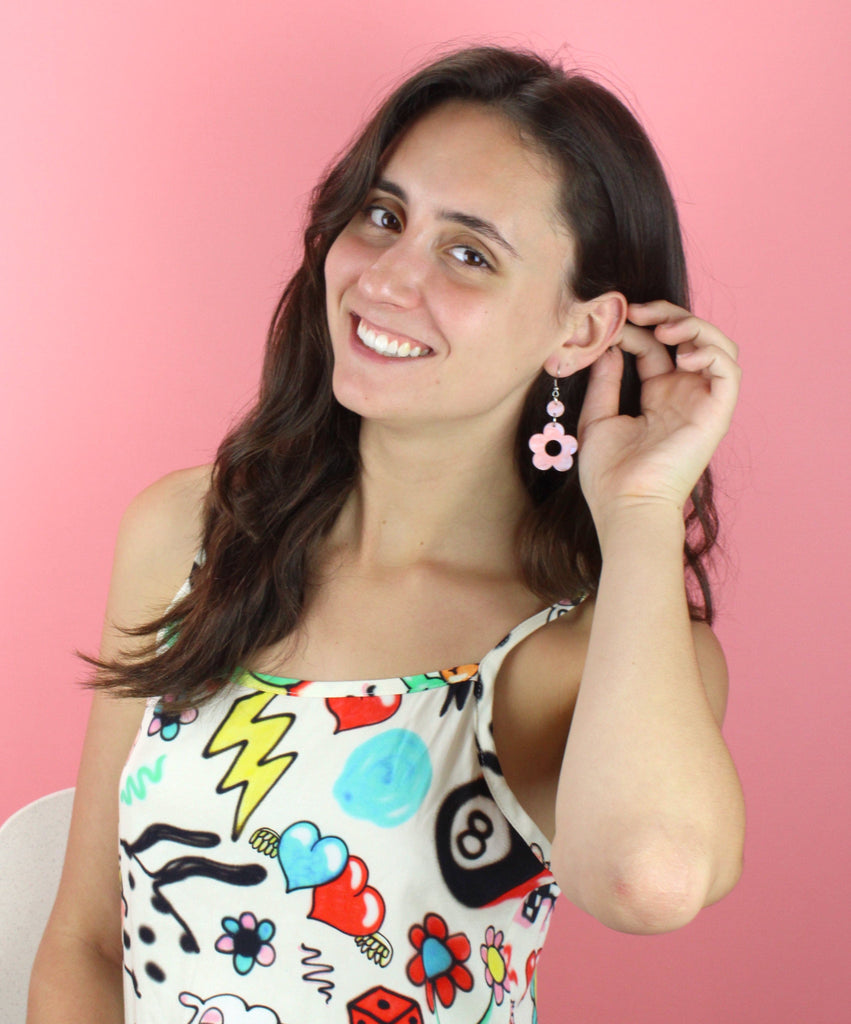 Model wearing pastel peach and blue perspex flower charms with cut out middle on stainless steel earwires