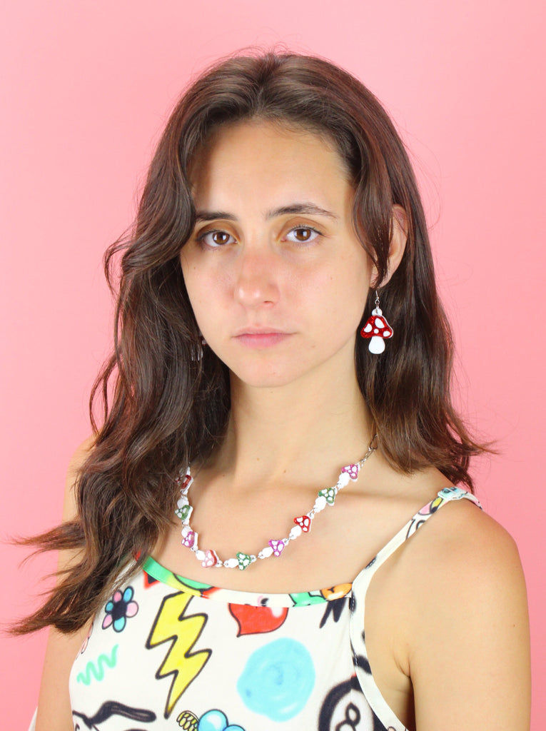 Model wearing oval chain necklace with red, green and pink glittery mushroom charms 