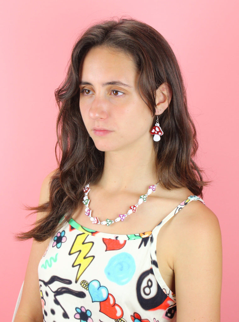 Model wearing oval chain necklace with red, green and pink glittery mushroom charms 