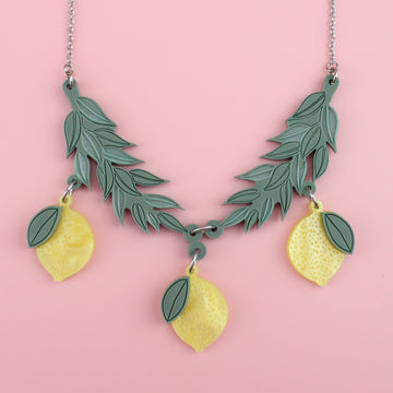 Yellow acrylic lemons hanging from matt sage green branches on a stainless steel chain