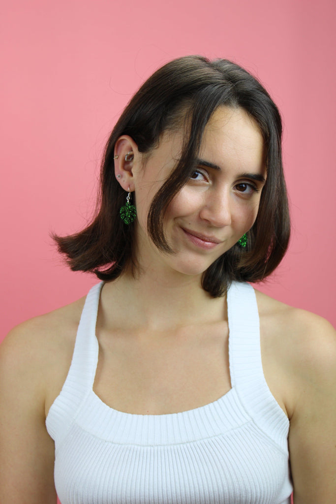 Model wearing Green glittery monstera charms on stainless steel earwires