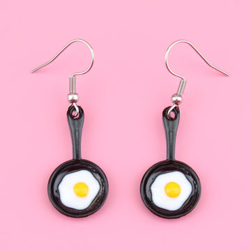 Charms that feature a fried egg in a frying pan on stainless steel earwires