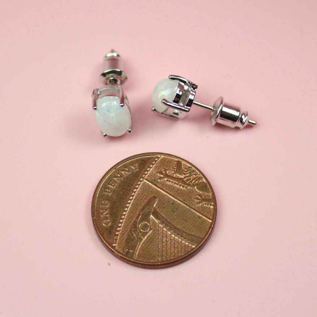 Small faux opal stud earrings with a penny next to it for scale