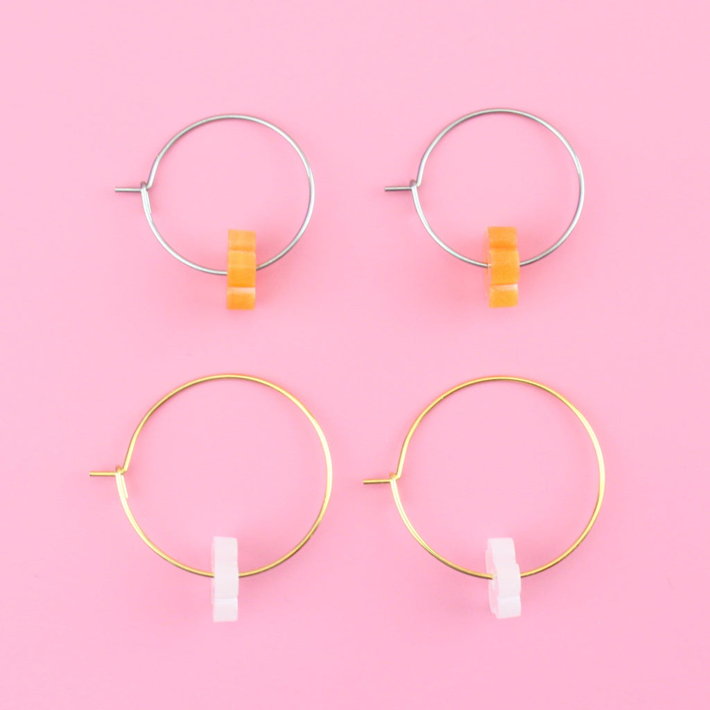 2 pack earring set showing orange flower charms on silver hoops and white flower charms on gold hoops
