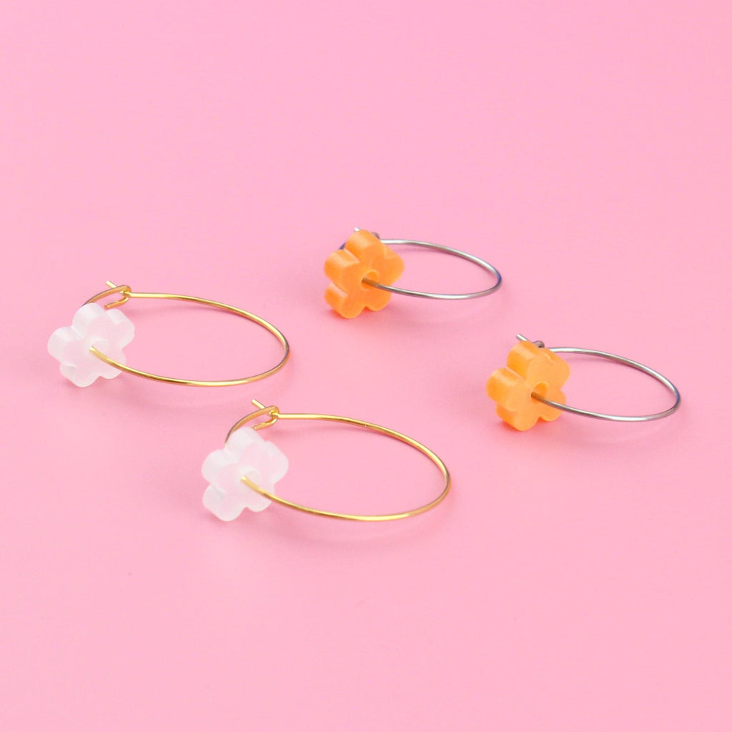 2 pack earring set showing white flower charms on gold hoops and orange flower charms on silver hoops