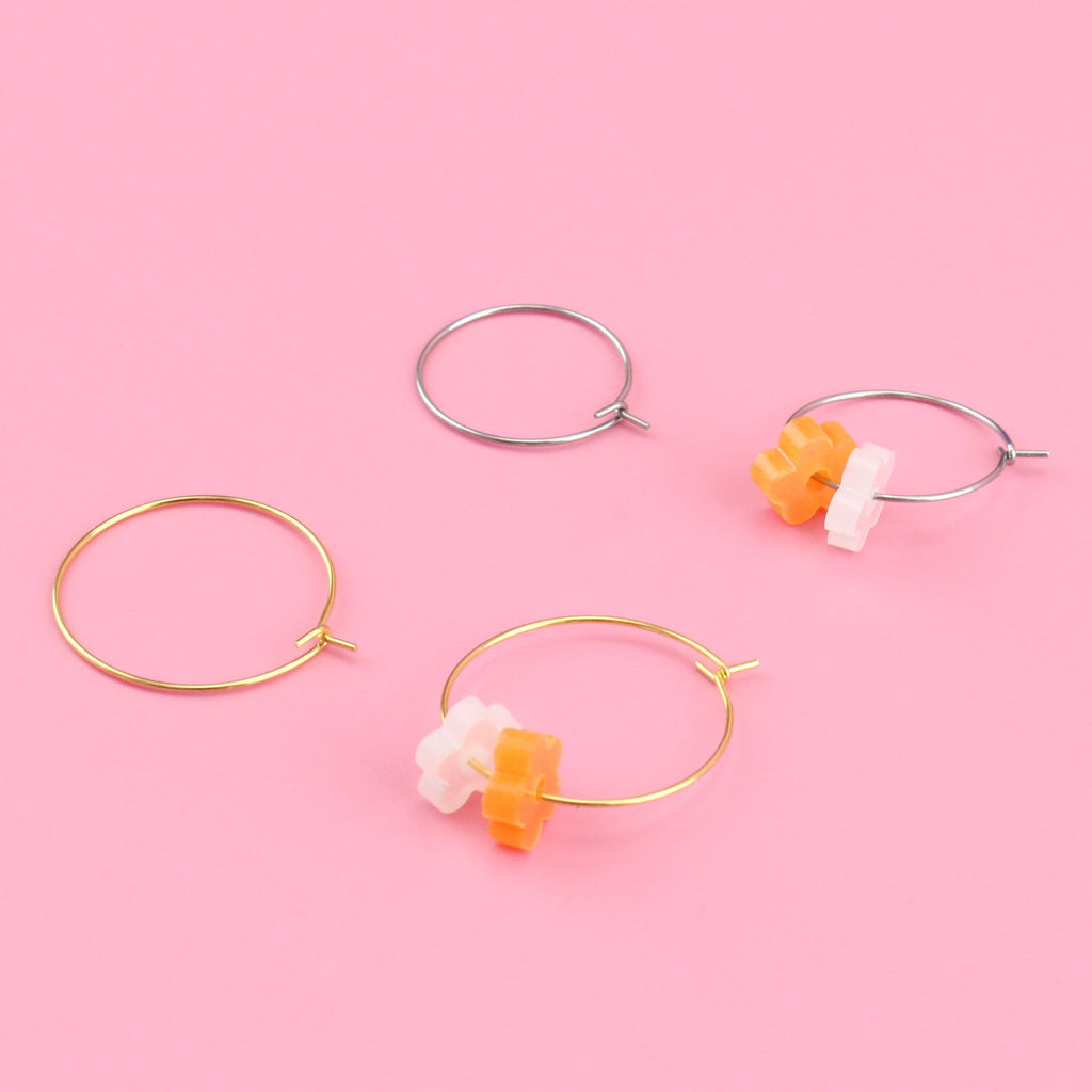 Showing both the orange and white flower charms on a gold hoop and on a silver hoop