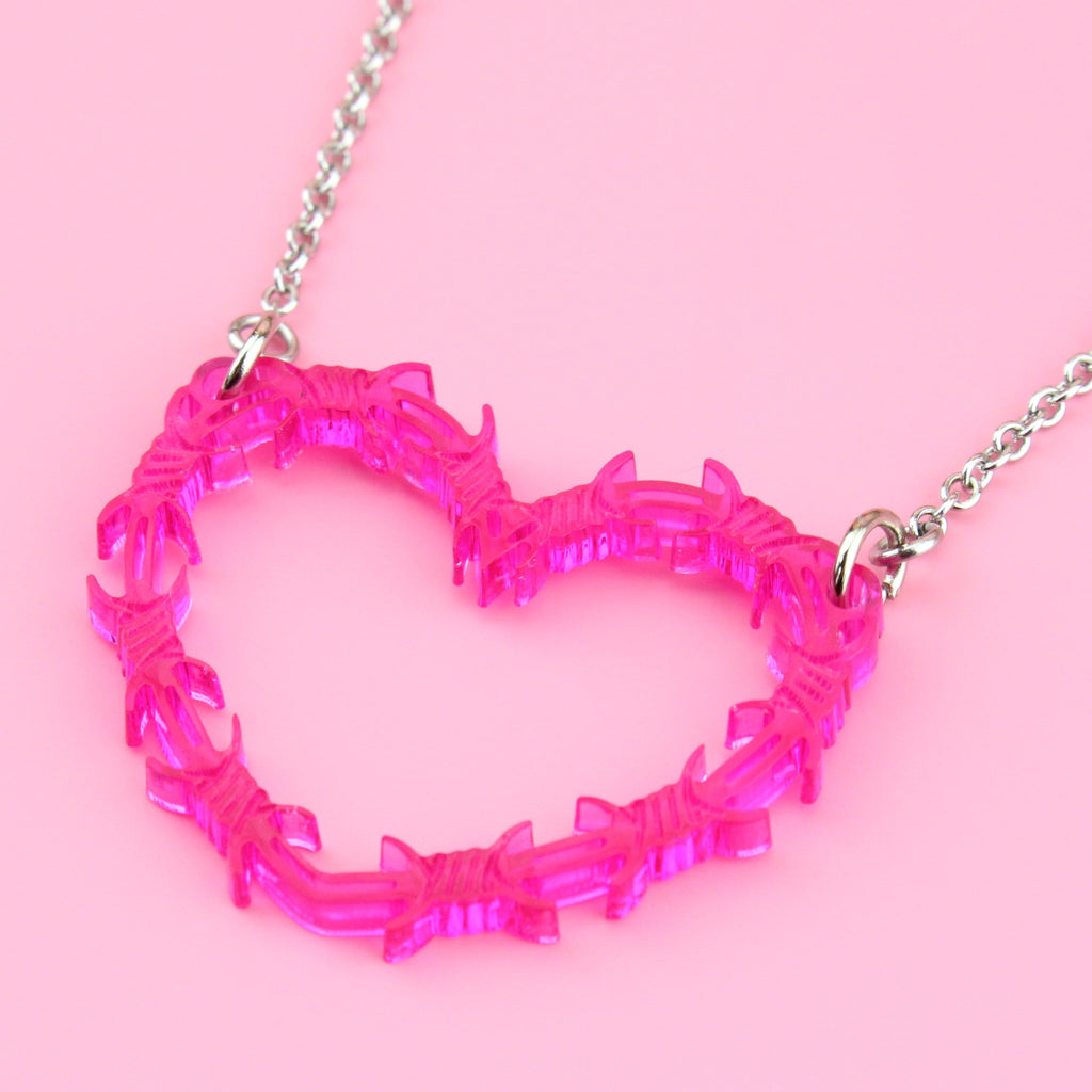 Pink barbed wire details in the shape of a heart on a stainless steel chain