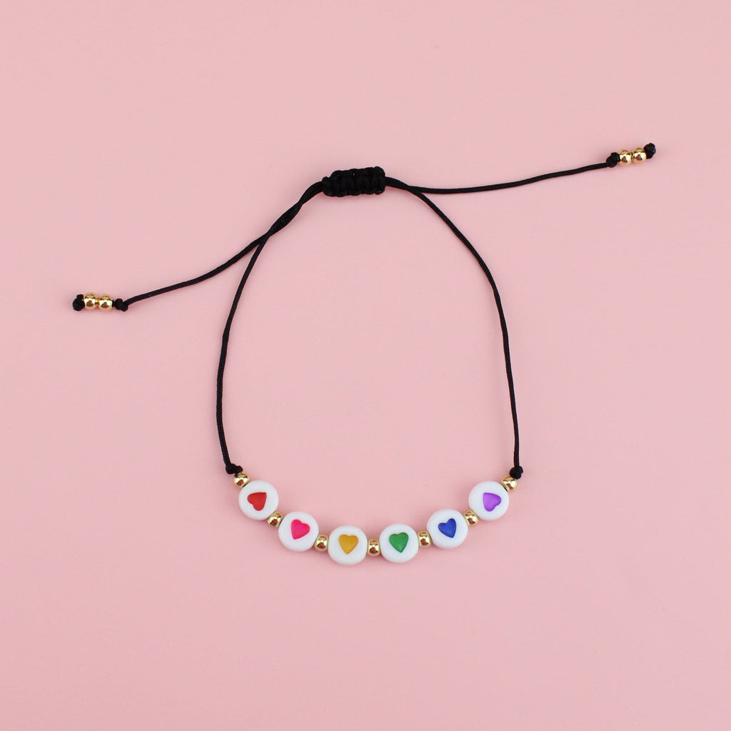 Adjustable nylon cord bracelet featuring white charms with red, pink, yellow, green, blue and purple hearts