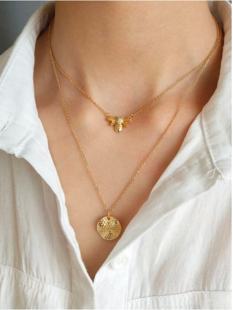 Model wearing gold plated stainless steel necklace featuring a gold disk honeycomb pendant