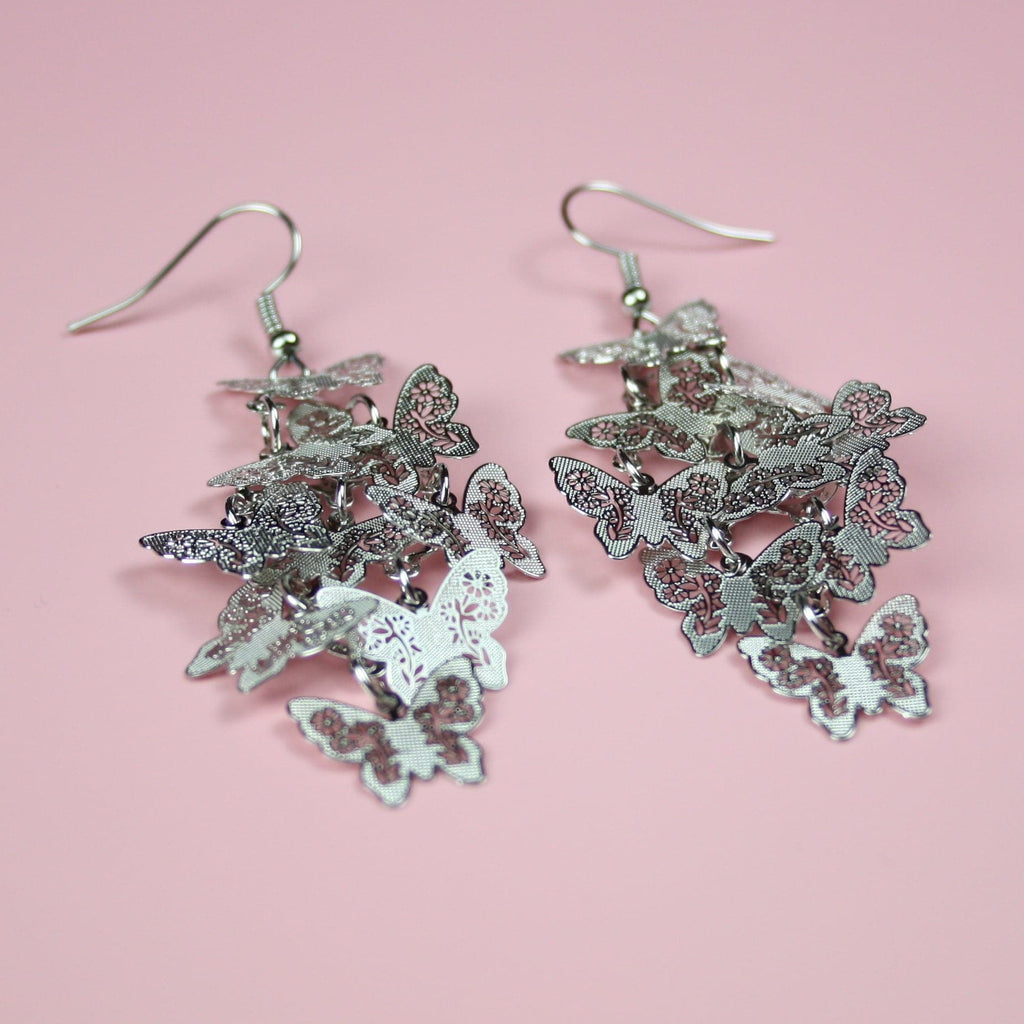 A cluster of silver butterfly earrings on stainless steel earwires