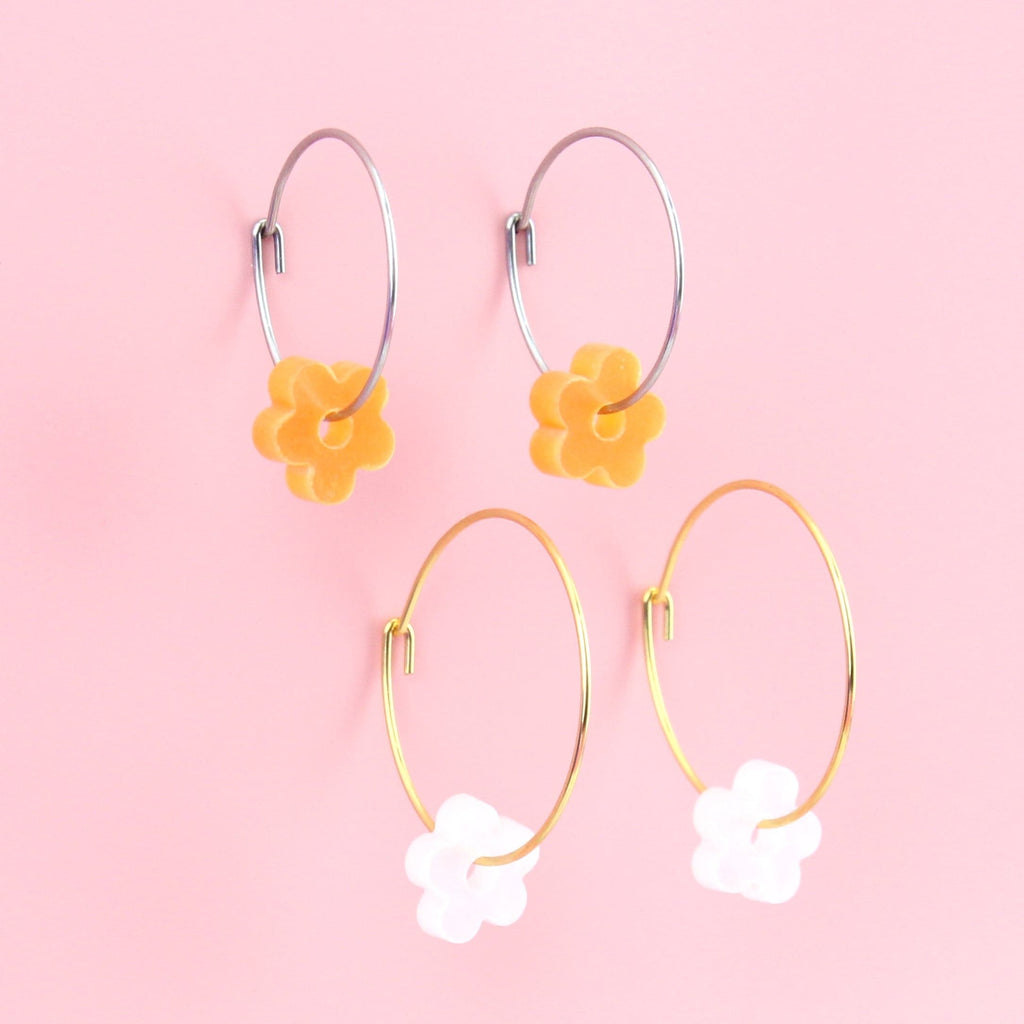 2 pack earring set showing orange flower charms on silver hoops and white flower charms on gold hoops